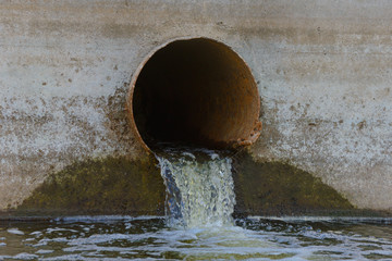 Sewer water spills out of an old rusty pipe