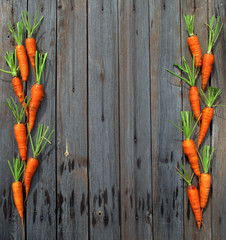 Orange sweet juicy carrots lie on old dark boards