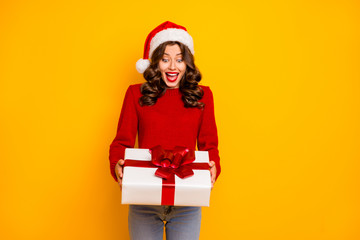Amazing lady holding large giftbox in arms wear knitted jumper and santa hat isolated yellow background