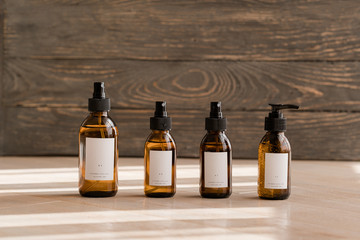 Set of cosmetic dark amber glass bottles with white labelson wooden background. Closeup, copyspace. Beauty blogging, salon treatment concept, minimalism brand packaging mock up - 291484045