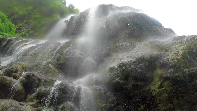 Bottom view on Tumpak Sewu waterfall on east Java, Indonesia.  water jets flying in a frame in slow motion