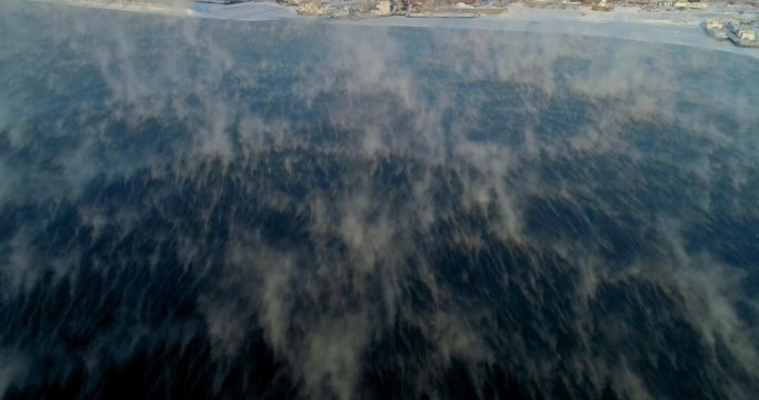 Aerial: Fog on flowing Angara River by snow covered cityscape - Irkutsk, Russia
