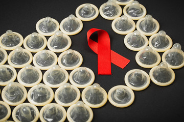 AIDS ribbon with condom on black background