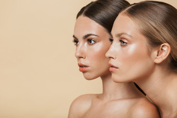 Women posing naked isolated over beige wall background.
