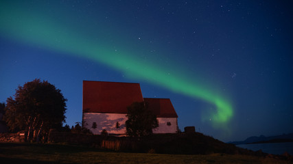 Nordlichter mit einer Kirche im Vordergrund auf den Ofoten