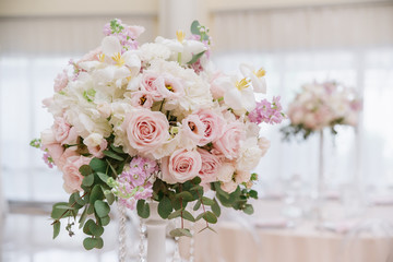 Large wedding flowers, white and cream roses, eucalyptus leaves decorate the banquet hall of the restaurant