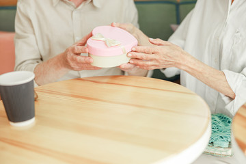 Elderly man giving cute gift box to his wife