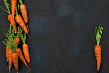 Appetizing juicy orange washed carrots stacked on a black velvet background