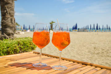 Two glasses of Aperol standing on wooden table on beach in Lido, Venice