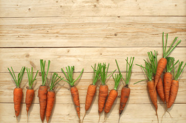Orange sweet carrots lie on a light wooden background