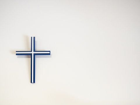 Blue and white catholic cross on a wall with copy space