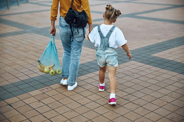 Woman walking with daughter and carrying food stock photo