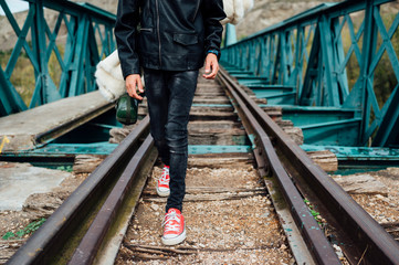 Kid hiking in the woods caring a sleeping bag walking in a train track