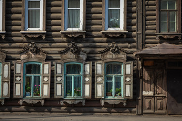 Fototapeta na wymiar Window with the wooden carved architrave in the old wooden house in the old Russian town. Irkutsk