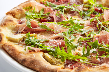 Tasty parma ham and artichoke pizza closeup