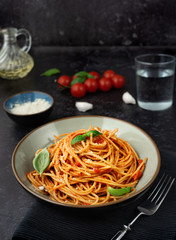 Pasta in a plate with tomato sauce on black background