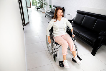 Smiling woman moving on wheelchair indoors stock photo