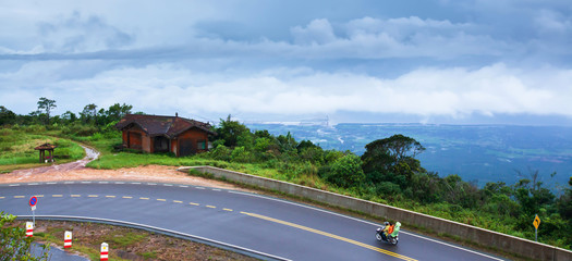 Khmer family driving motorcycle on the mountain asphalt road.