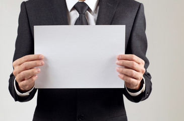 Businessman holding a blank white sheet for text space.
