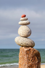 Rock zen pyramid of white pebbles on the background of the sea. Concept of balance, harmony and meditation.