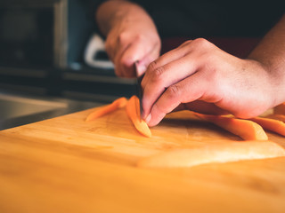 close up of professional young cook cutting carrots. hands detail