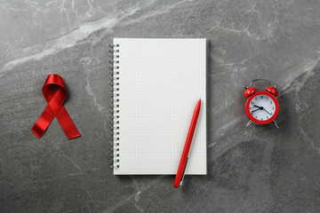 red ribbon with alarm clock on empty notebook