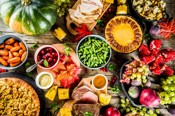 Thanksgiving family dinner setting concept. Traditional Thanksgiving day food  with turkey, green beans and mashed potatoes, stuffing, pumpkin, apple and pecan pies, rustic wooden table