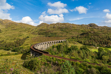 Looking down on the Glenfinnan Viaduct in the Scottish Highlands with rugged green mountains behind