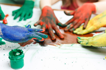hands in paints on background of light table painted in different colors