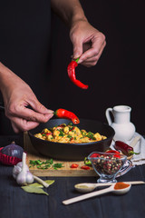 pan with meat in sauce with chili pepper on a dark background