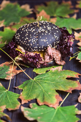 black bread burger with healthy meat and leaves of brown salad on paper