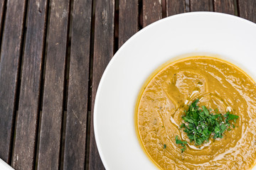 sweet potato soup on white plate. Wooden background
