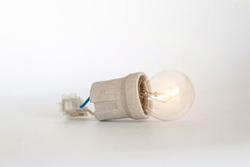 Lighting incandescent lamp bulb with cap, socket, wires and terminal block lies on white...