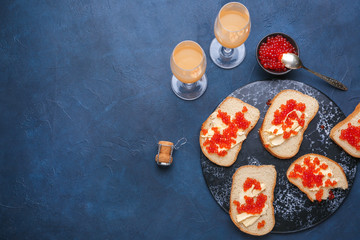 Bread with red caviar, butter and glasses of champagne on dark table