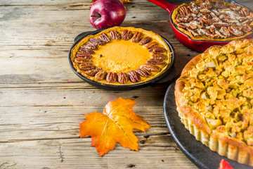 Traditional seasonal autumn pies - pumpkin, pecan and apple crumble cakes, wooden background © ricka_kinamoto