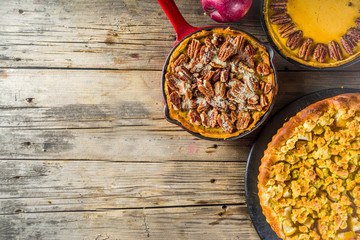 Traditional seasonal autumn pies - pumpkin, pecan and apple crumble cakes, wooden background © ricka_kinamoto