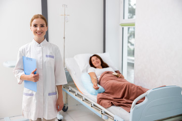 Obraz premium Happy female doctoe is standing near bed in clinic