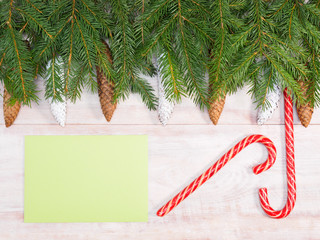 Christmas background with fir branches, cones, snowflakes, caramel and green envelope on brown wooden background. Christmas and New Year concept