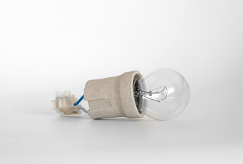 incandescent lamp bulb with cap, socket, wires and terminal block lies on white background, new idea concept