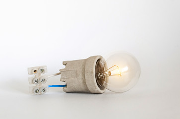 Lighting incandescent lamp bulb with cap, socket, wires and terminal block lies on white...