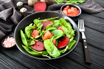 Plate with tasty salad on dark table