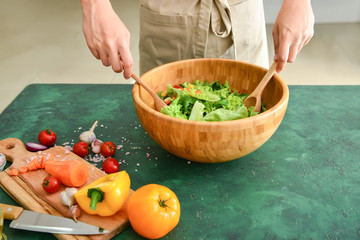 Woman preparing tasty salad at table, closeup