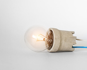 Lighting incandescent lamp bulb with cap, socket, wires lies on white background, new idea concept