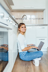 Business woman drinking a cup of coffee and using her laptop for working in some bright morning. Wearing casual outfit.