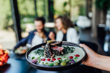 Healthy lean grilled medium-rare beef steak and vegetables with roasted pumpkin and a leafy green herb salad in a rustic pub or tavern.
