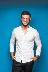 Fototapeta premium Young handsome freelancer in white shirt posing on blue background. Success concept.