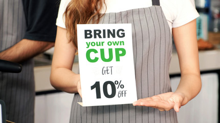 Bring your own cup get discount, Close up of waitress hand holding zero waste promotion poster at...