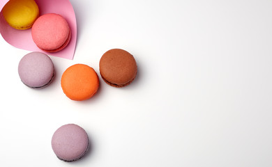baked macarons in a pink paper bag on a white background
