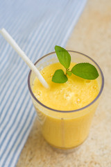 Blended smoothie on table. yellow juice on blue textile background. Fresh organic smoothie, healthy drink with fresh fruit.