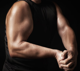 Fototapeta na wymiar adult man with a sports figure in black clothes strained his muscles in his arms
